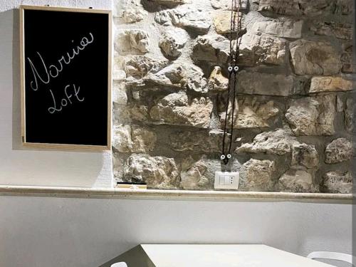 a stone wall with a sign in front of a bench at Narnia Loft in Narni