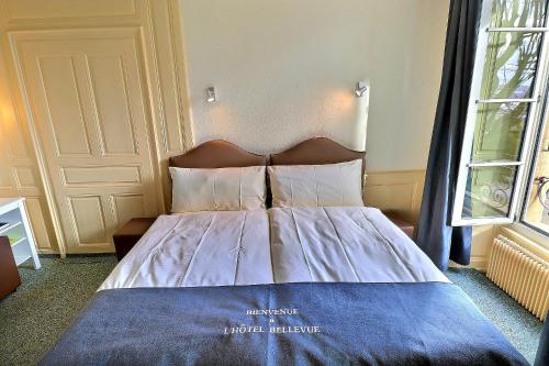 a bedroom with a bed with a blue comforter at Hôtel Restaurant Bellevue in Onnens