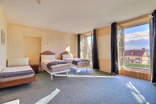 a bedroom with two beds and a large window at Hôtel Restaurant Bellevue in Onnens