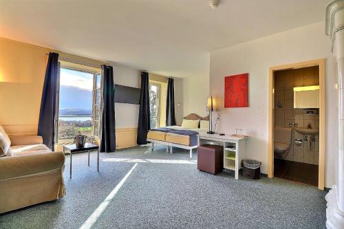 a hotel room with a bed and a desk and a couch at Hôtel Restaurant Bellevue in Onnens