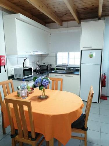 a kitchen with a table with a vase of flowers on it at Casa da Isabel in São Roque do Pico