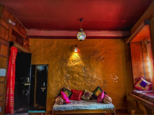 a room with a couch with colorful pillows on it at Mud Mirror Guesthouse in Jaisalmer