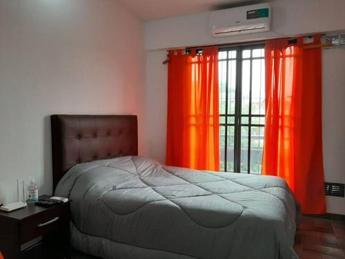 a bedroom with orange curtains and a bed and a window at Alquiler Temporario Azcuénaga in Morón