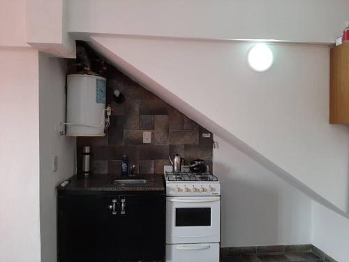 a kitchen with a sink and a stove and a staircase at Alquiler Temporario Azcuénaga in Morón