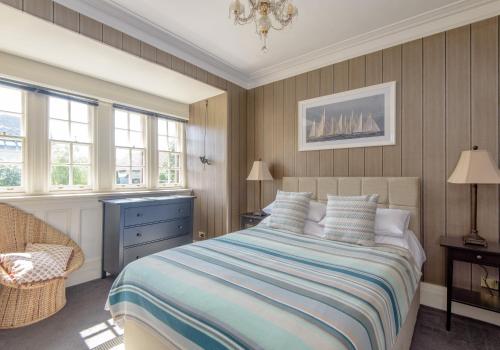 a bedroom with a bed and a chair and windows at St Aidans in North Berwick