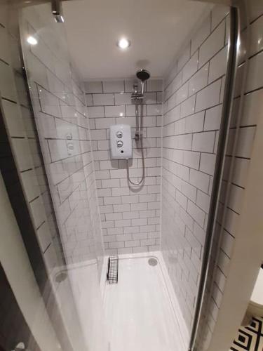 a bathroom with a shower with a white tiled wall at The Vault - boutique apartment in the centre of King's Lynn in King's Lynn