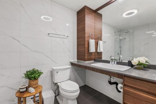 a white bathroom with a toilet and a sink at Modern Studio at Blackcomb base in Whistler
