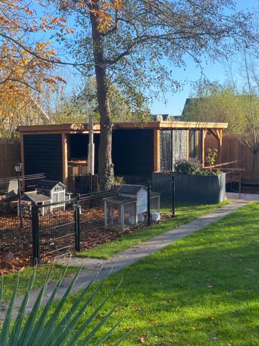 a house with a fence in a yard at Casa aan de Plas, B&B met sauna en hottub of jacuzzi in Nieuwkoop