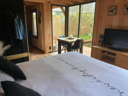 a bedroom with a bed and a television and a table at Casa aan de Plas, B&B met sauna en hottub of jacuzzi in Nieuwkoop