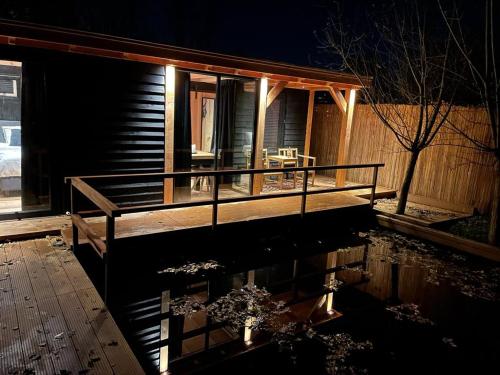 a house with a porch with a reflection in the water at Casa aan de Plas, B&B met sauna en hottub of jacuzzi in Nieuwkoop