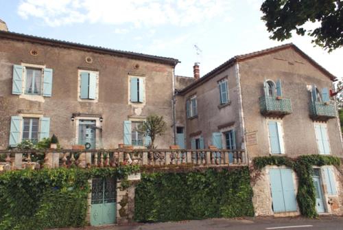 a large brick building with a fence in front of it at Les Chimères in Puylaroque