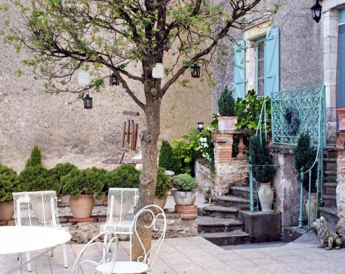 a patio with a table and chairs and a tree at Les Chimères in Puylaroque