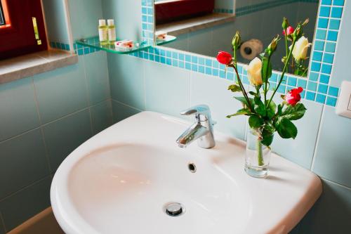 a bathroom sink with a vase with roses in it at Nido Verde in Agerola