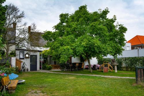 ein Haus mit einem Baum im Hof in der Unterkunft B&B De Kreek in Graauw