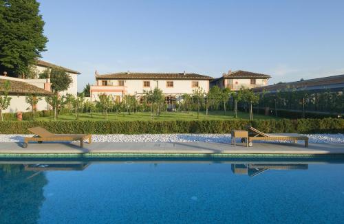 una piscina con 2 bancos frente a un edificio en Villa Olmi Firenze en Florence