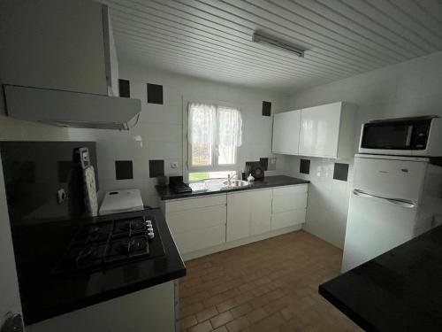 une cuisine avec des armoires blanches et un four à plaques de cuisson dans l'établissement Maison proche de l'aéroport CDG-Paris, à Goussainville