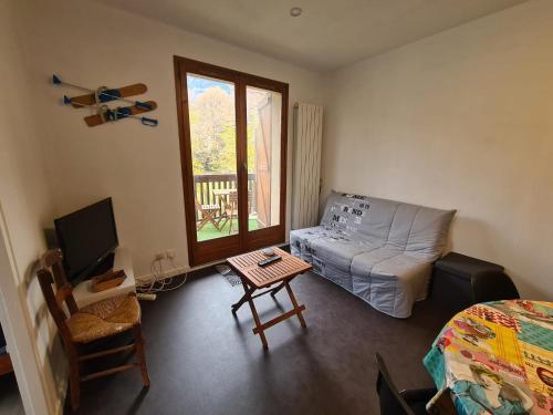 een woonkamer met een bank, een tafel en een televisie bij Très joli appartement 4-6 personnes dans Luchon in Luchon