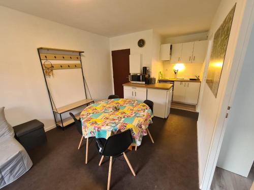 Habitación pequeña con mesa, sillas y cocina. en Très joli appartement 4-6 personnes dans Luchon en Luchon