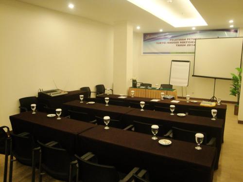 a conference room with tables and chairs and a screen at Top Hotel Manado by Gran Puri in Manado
