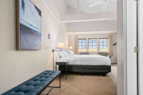 a white bedroom with a bed and a bench in it at Saratoga Inn in Langley
