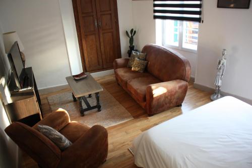 a living room with leather furniture and a bed at Bel appartement indépendant centre de Magny-Cours avec parking in Magny-Cours