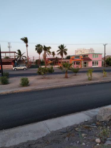 eine leere Straße mit Palmen und einem rosa Gebäude in der Unterkunft Hotel Duve Coral in Loreto