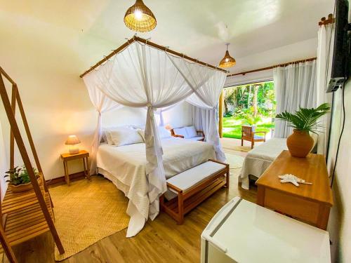 a bedroom with a canopy bed and a table at Pousada Recanto Caxando in Trancoso