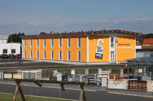 an orange building with a sign on it next to a parking lot at Fair-Price-Hotel in Bad Waltersdorf