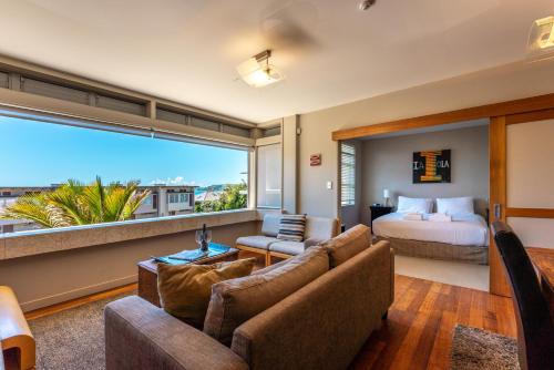 a hotel room with a bed and a large window at The Sands - Apartment 12 - Stay Waiheke in Onetangi