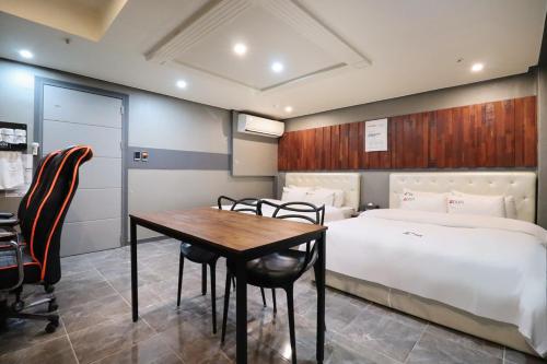 a bedroom with a bed and a table and chairs at Hotel Don in Changwon