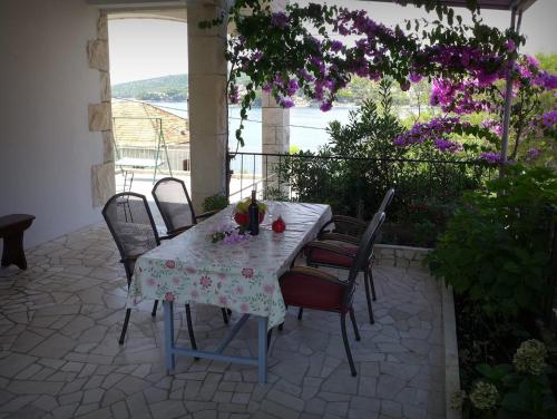 uma mesa e cadeiras num pátio com flores roxas em Apartment Mari - 30 m from sea em Sumartin