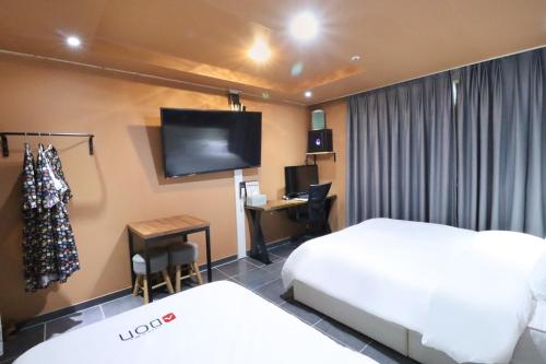 a hotel room with a bed and a desk and a tv at Hotel Don in Changwon