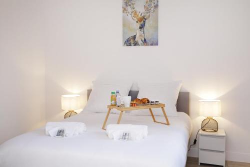 a bedroom with a white bed with a table on it at Cocon Cosy Flat - Hyper-Centre Senlis in Senlis