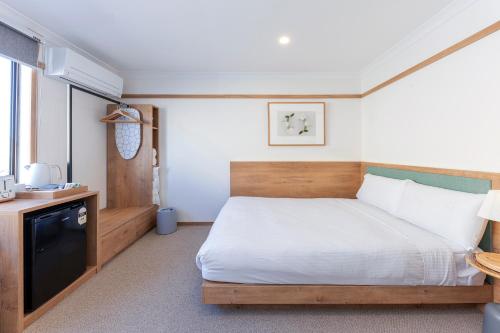 a small bedroom with a bed and a television at Blue Ocean Motel Apollo Bay in Apollo Bay