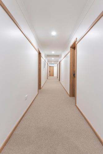 an empty corridor in an office building with white walls and an open door at Blue Ocean Motel Apollo Bay in Apollo Bay