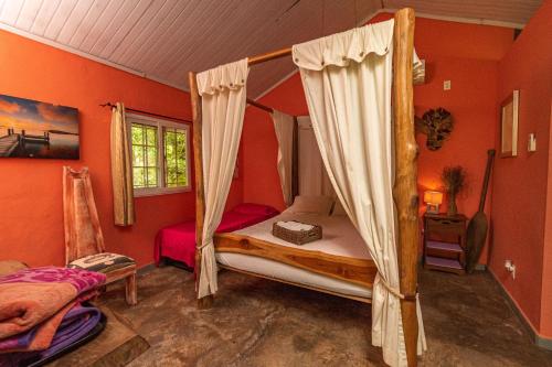 a bedroom with a canopy bed and orange walls at Monkey Lodge Panama in Chilibre