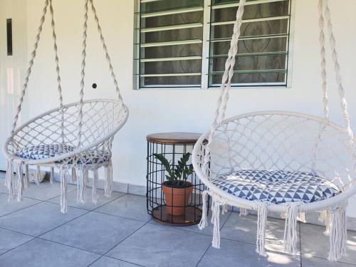 two swinging chairs and a table in a room at Aguadilla Sunset Apt AC WiFi 8 minute walk Crashboat Beach in Aguadilla