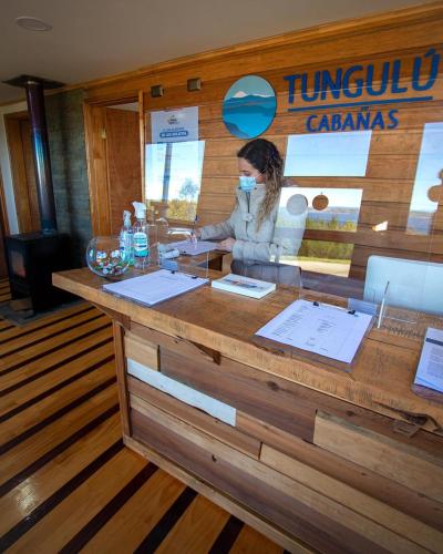 a woman wearing a face mask behind a counter at Cabañas Tungulú in Puerto Montt