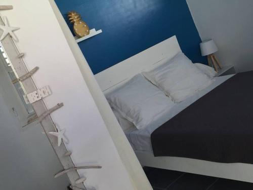 - une chambre avec un lit et un mur bleu dans l'établissement Eden Location, à Les Trois-Îlets