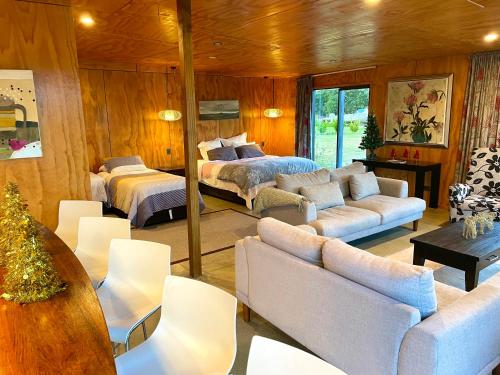 a living room with two beds and a couch at The Camel at Araiawa Raio Lodge Pukenui in Pukenui