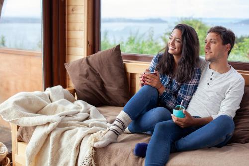 a man and a woman sitting on a bed at Cabañas Tungulú in Puerto Montt