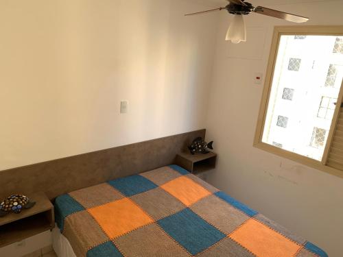 a bedroom with a bed with a blanket on it at Apartamento Enseada in Guarujá