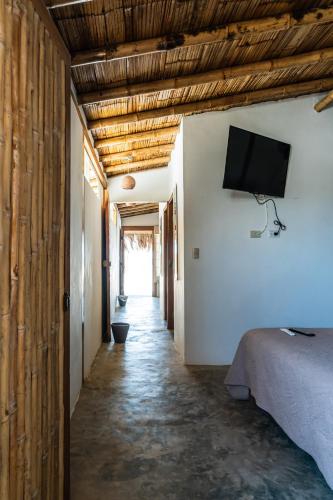 a hallway with a bed and a television on a wall at Vistazul in Vichayito