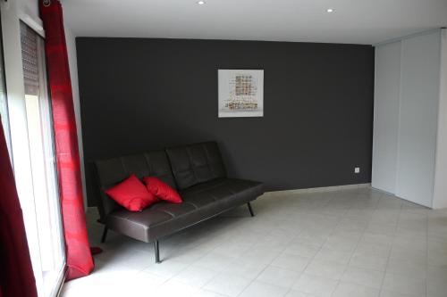 a black room with a couch with a red pillow at La Résidence Les Grands Vignobles in Libourne