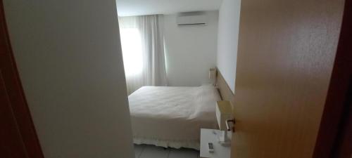 a bedroom with a white bed and a window at ILOA Ap inteiro - 2 suites sala cozinha in Barra de São Miguel