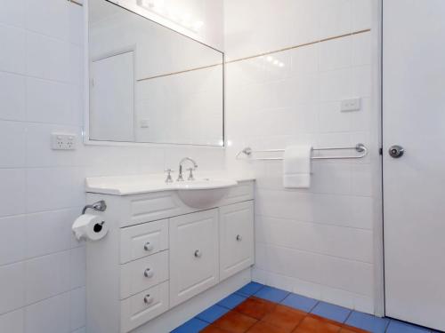 Un baño blanco con lavabo y espejo. en Horizons Retreat, en Salamander Bay