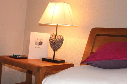 a lamp sitting on a table next to a bed at Hotel Des Falaises in Villers-sur-Mer