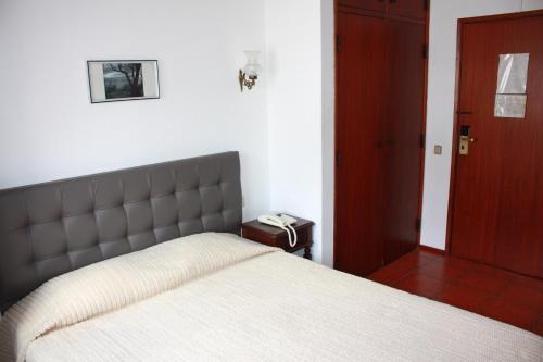 a bedroom with a bed and a phone on a table at Hotel Dona Leonor in Caldas da Rainha