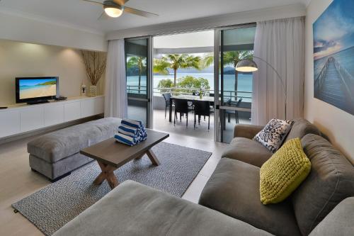 Frangipani Apartments on Hamilton Island by HIHA في جزيرة هاميلتون: غرفة معيشة مع أريكة وطاولة