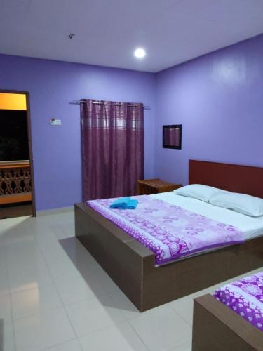 Un dormitorio con una cama y una pared morada. en Inapan Aishah, en Pantai Cenang